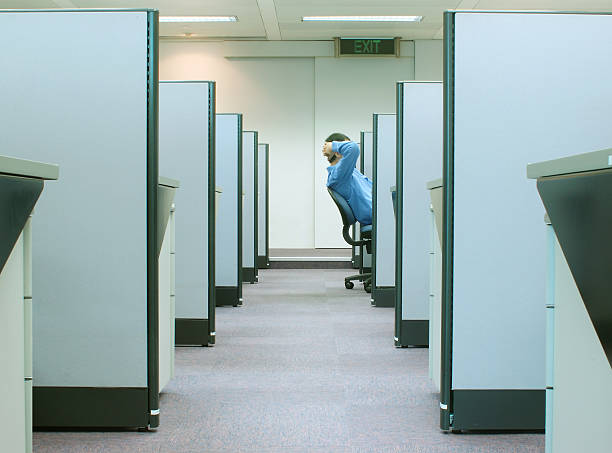 cubicles - office series 2 man reclining on his chair in cubicle with EXIT sign above stock cubes stock pictures, royalty-free photos & images