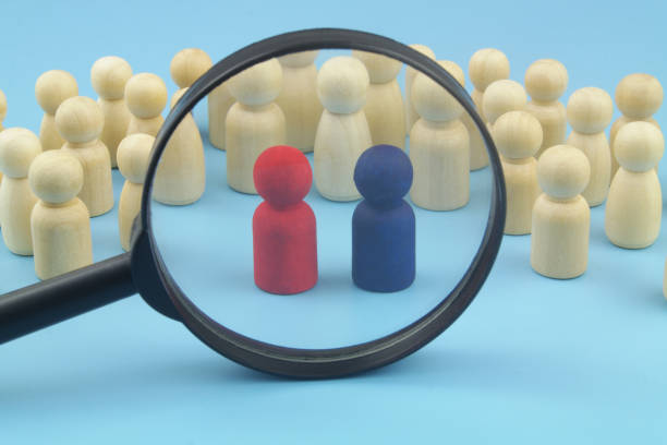istock Many people figures and two red and blue leaders under magnifying glass. 1395339271