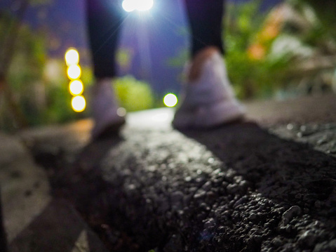 Blurred images of runners of white shoes on the street with bright lights at night.