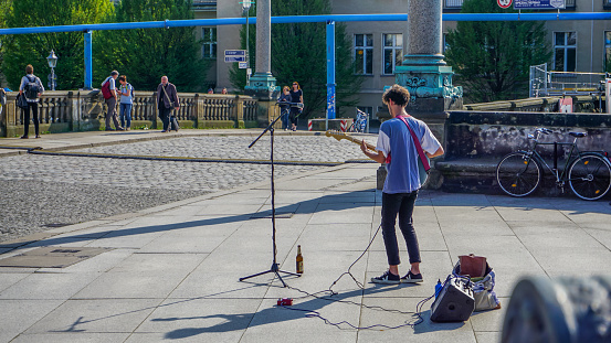Berlin, Germany-May 2018: Local street artist musician performing live music on the street in the walking district of the city centre. Young men performing his music for the people in the city.