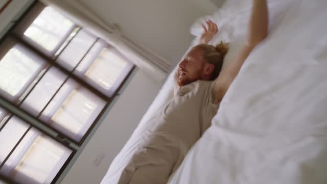 Caucasian man falls contentedly on the bed in slow motion