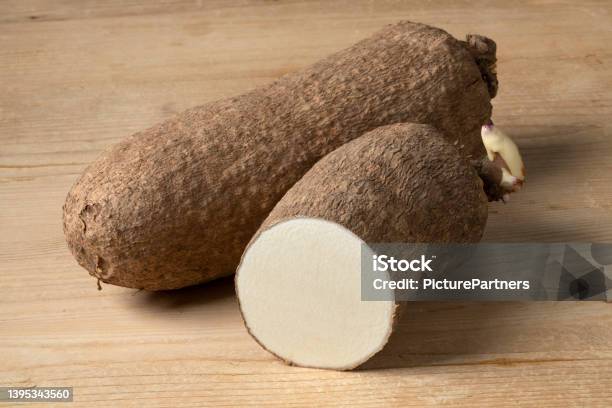 Whole And Halved Raw African Yam On Wooden Background Stock Photo - Download Image Now