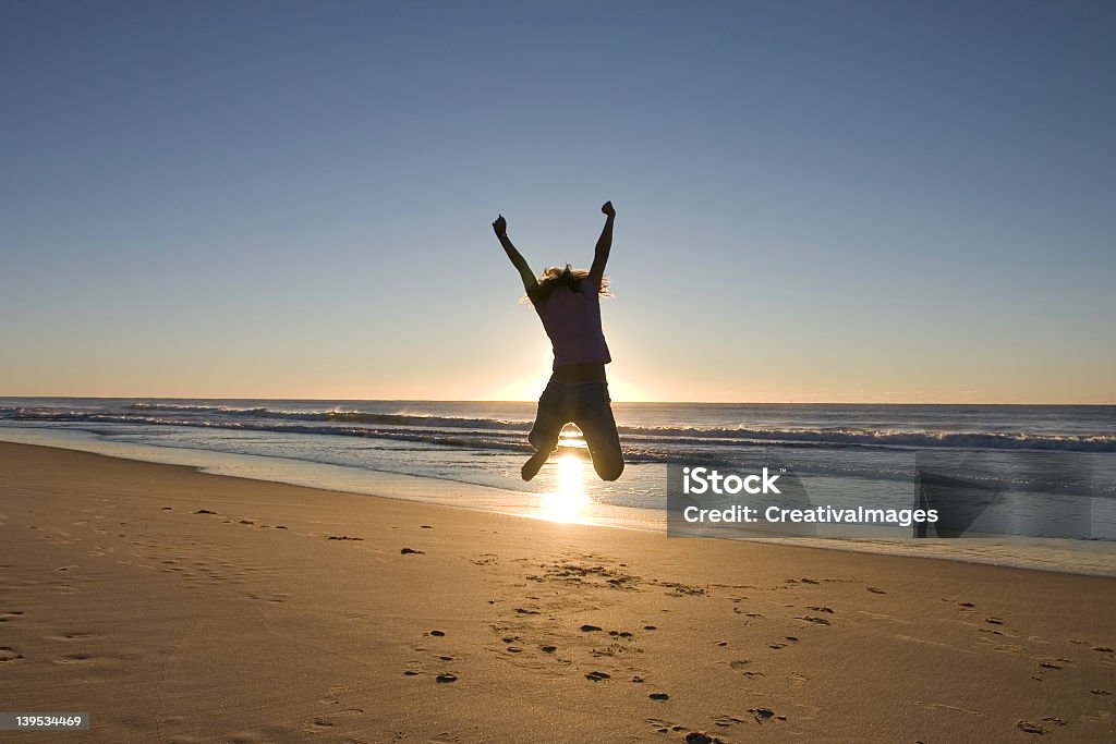 Man jumping high up at the beach during sunrise Expressing Freedom at the beach 20-29 Years Stock Photo