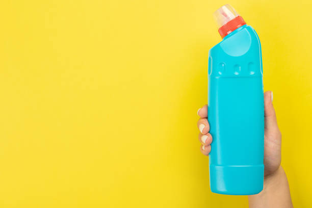 istock Cleaner's hand holding a  chemical spray bottle. Empty space for text or logo on a yellow background. Early spring or regular cleaning. Cleaning and cleaning concept. 1395346072