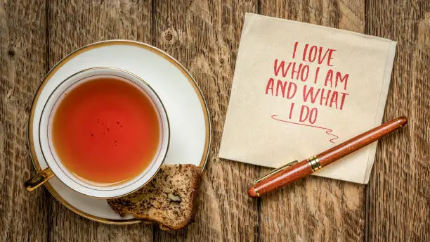 I love who I am and what I do - positive affirmation words on a napkin with a cup of tea, self esteem and personal development concept