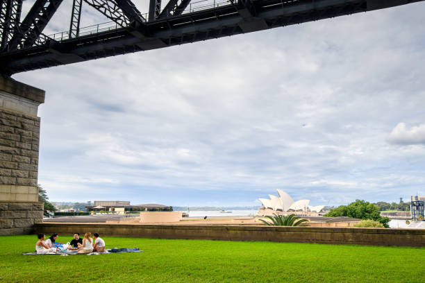 les gens pique-niquent sous le pont du port de sydney - opera house sydney australia australia bay photos et images de collection