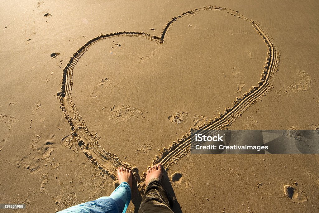 Heart on the beach Couple drawing a heart on the beach Adult Stock Photo