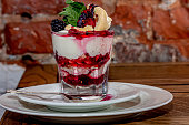 Cup of ice cream with fruits and nuts, sundae with cherries, raspberries and blueberries,