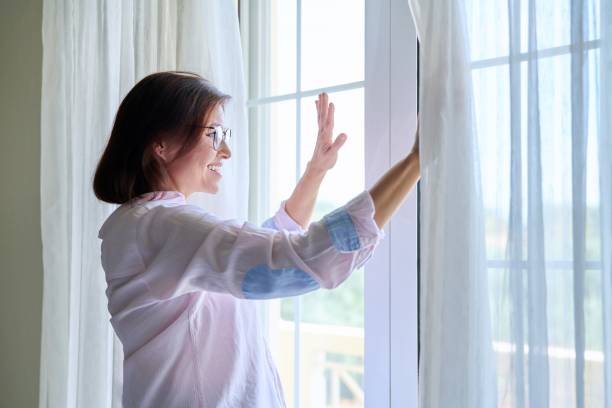 istock Smiling positive middle aged woman looking out the window 1395351768