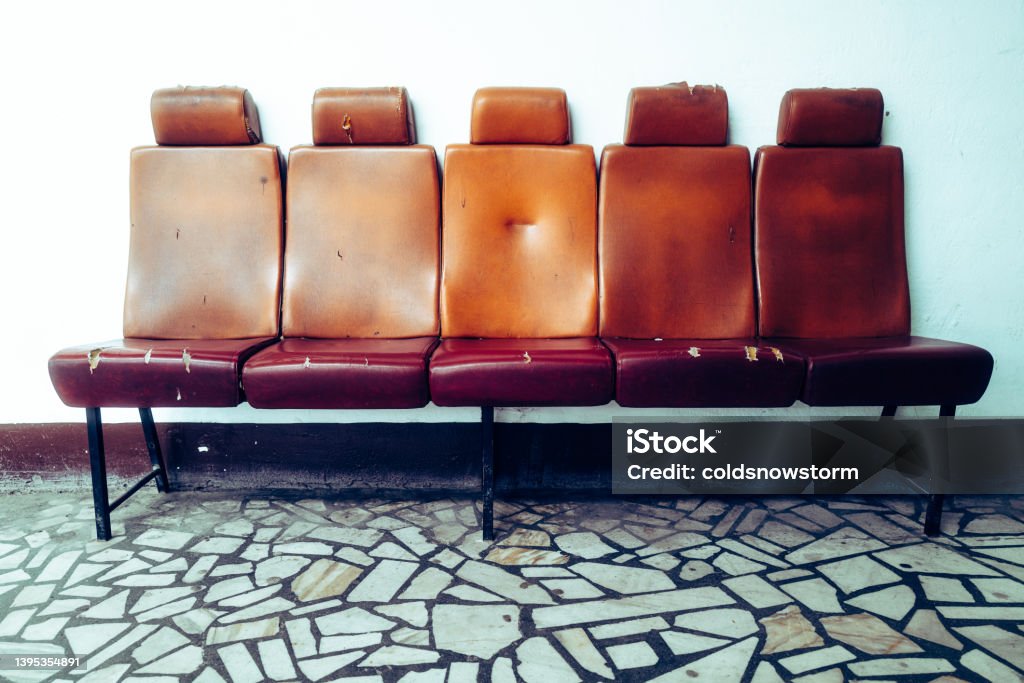 Old destroyed red seats in a row in waiting room A bank of five red leather seats in a row in a waiting room. The seats are old and the leather is torn and destroyed. Abandoned Stock Photo