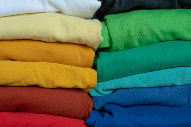 istock Stacks of multicolored fabrics in cool and warm colors are compared next to each other. Background with folded clothes with blank space for information. T-shirts of different colors 1395355090