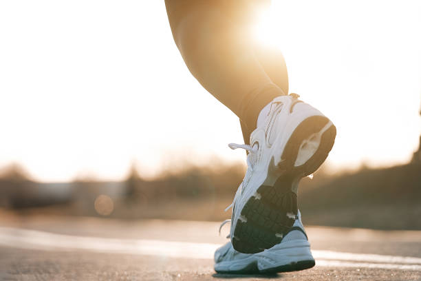 Runner feet running on road closeup on shoe Runner feet running on road closeup on shoe. Young athlete on sunset run at park distance running stock pictures, royalty-free photos & images