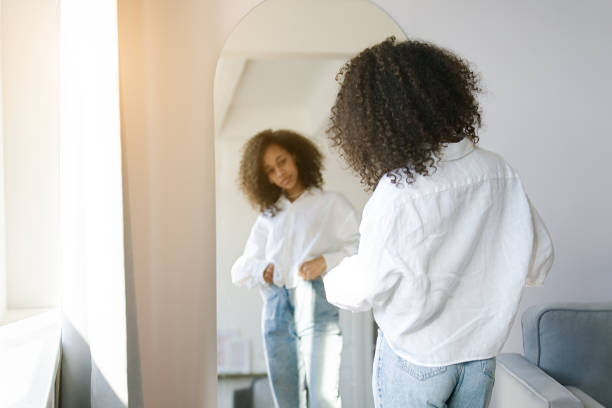 アフリカ系アメリカ人の女の子は、私はリビングルームの鏡の前で着る服を選ぶ - 試着室 ストックフォトと画像