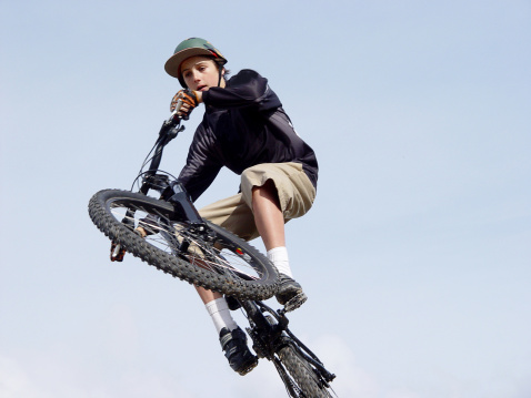Closeup of a boy jumping on a mountain bike, blue sky background