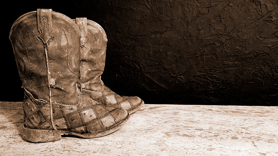 Western - Worn, dirty kids cowboy boots.  Pair of kids boots.  They have been well used and worth every cent.  Looks like this kid lived in those boots.  Sepia toned.
