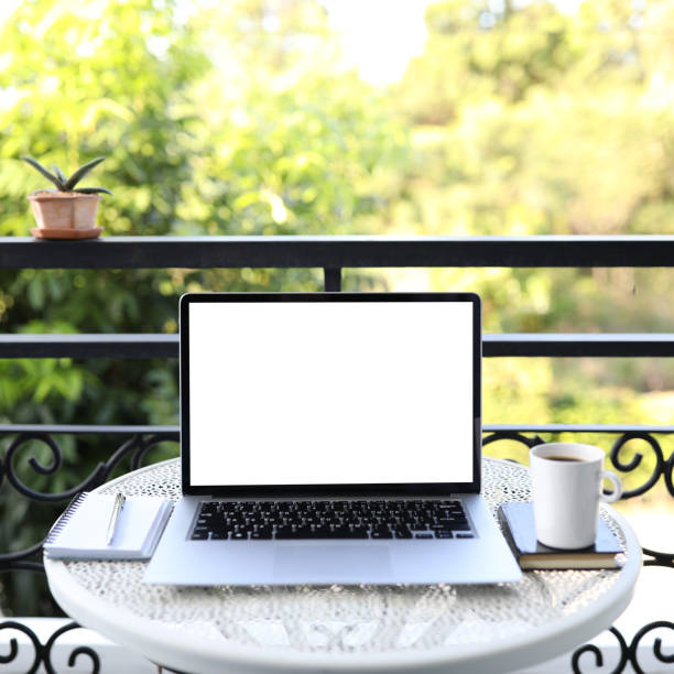 istock Laptop side view and coffee cup with notebooks on white table outdoor 1395359258
