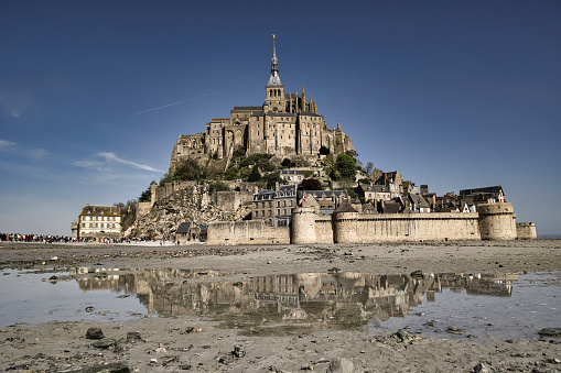 Panoramic view of famous historic Le Mont Saint-Michel tidal island on a sunny day with blue sky and reflections