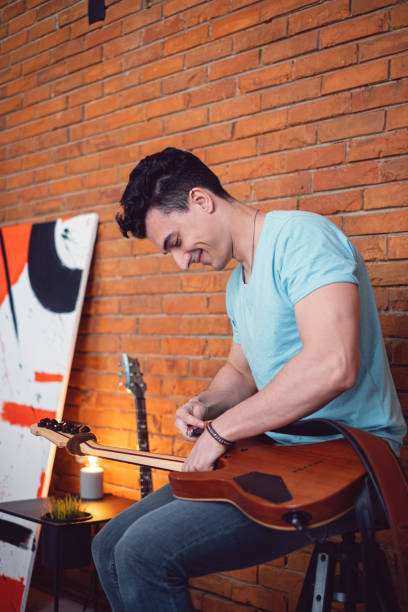 istock Young male musician adjusting his electric guitar for practise 1395360486