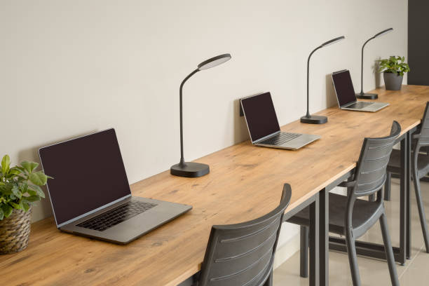 varias computadoras portátiles de pie en fila sobre una mesa de madera. lugares de trabajo. - classroom education chair carpet fotografías e imágenes de stock