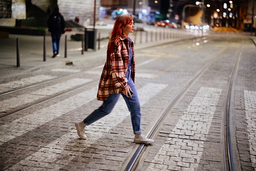 Traffic lights at night. Woman walking in the city at night