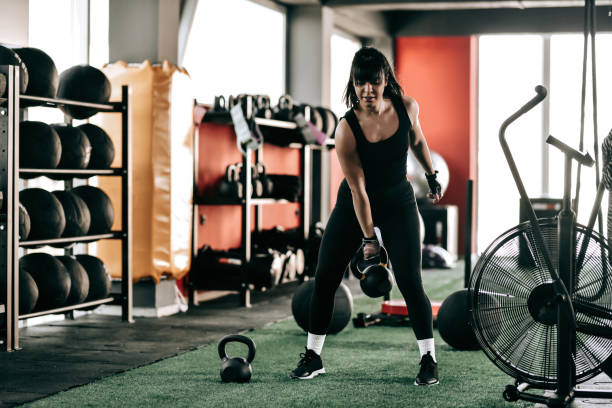 istock Athletic Female In Gym Practicing One Arm Kettlebell Swings 1395365426