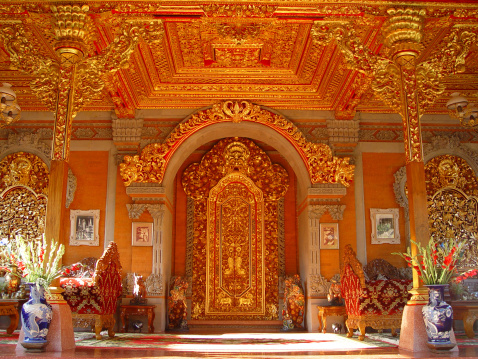Temple in the King's palace in Bali showing reds and bright golds. Image shows the grand enterence into the temple with two large doors
