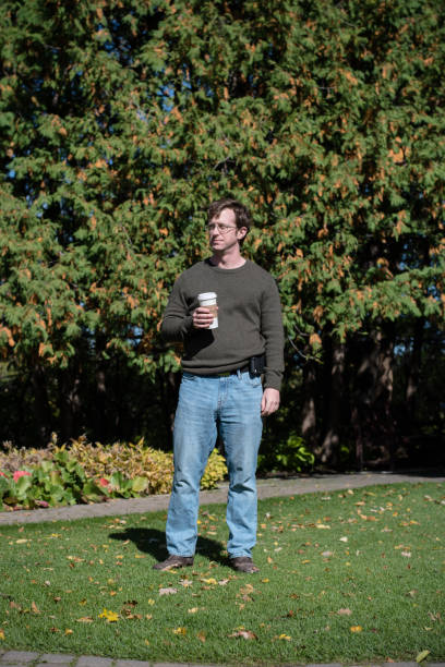 Bored Man with a coffee, squints in the sunlight.