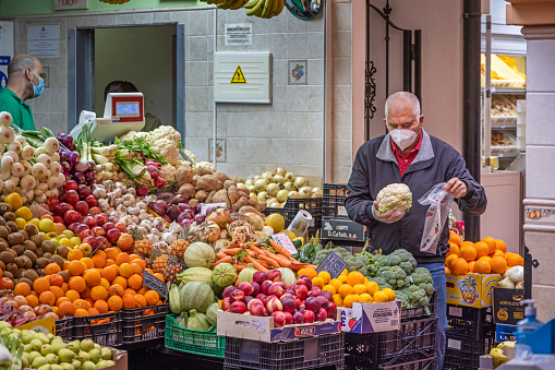 Customer selecting his favorite cabbage at a greengrocers market stall in the public marketplace Cooperativa Mercado Nuestra Señora De África which is partly under roof and established in 1943 in the center of Santa Cruz which is the main city on the Spanish Canary Island Tenerife