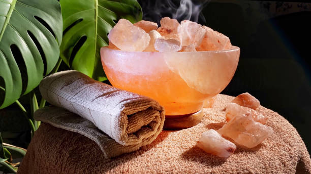 himalayan salt lamps and towel rotating on table in dark room. Boost mood, improve sleep, ease allergies, reduce anxiety and clean the air. Copy space stock photo
