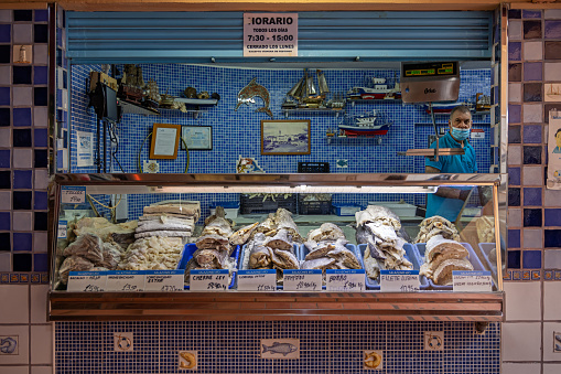 Fishmonger in a market stall selling dried fish in the public marketplace Cooperativa Mercado Nuestra Señora De África which is partly under roof and established in 1943 in the center of Santa Cruz which is the main city on the Spanish Canary Island Tenerife