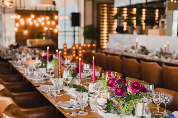 istock Table setting at the wedding reception. Floral compositions with beautiful ranunculus flowers and greenery, candles, laying and plates on a decorated table. 1395370344