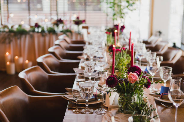 istock Table setting at the wedding reception. Floral compositions with beautiful ranunculus flowers and greenery, candles, laying and plates on a decorated table. 1395370358