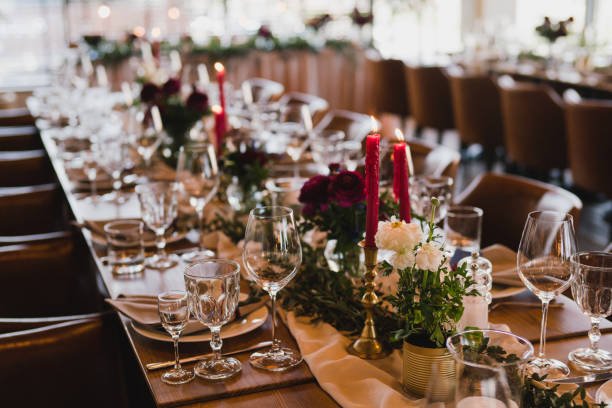 istock Table setting at the wedding reception. Floral compositions with beautiful ranunculus flowers and greenery, candles, laying and plates on a decorated table. 1395370373