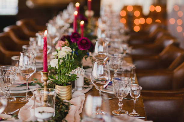 istock Table setting at the wedding reception. Floral compositions with beautiful ranunculus flowers and greenery, candles, laying and plates on a decorated table. 1395370421