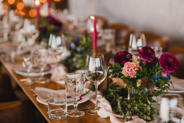 istock Table setting at the wedding reception. Floral compositions with beautiful ranunculus flowers and greenery, candles, laying and plates on decorated table. 1395370438