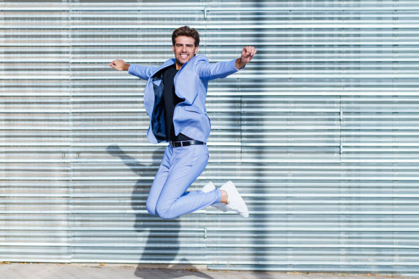 istock Young man wearing a suit jumping outdoors 1395372549
