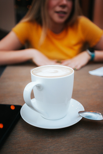 Cup of coffee, on the table in the middle of a conversation between two people.