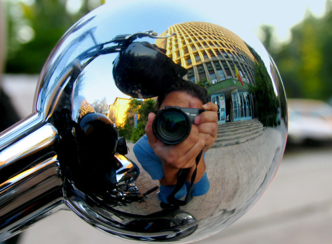 Macro of a photographer reflected image in a motorbike spherical signalling device ( nickelled part )