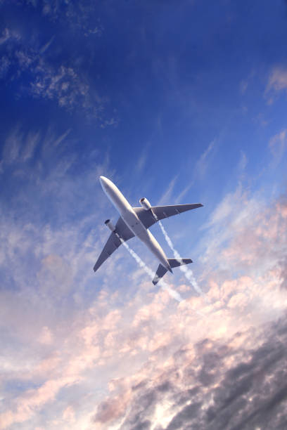 Vertical nature background with aircraft and Jet trailing smoke in sunset sky. Airplane and condensation trail Vertical nature background with aircraft and Jet trailing smoke in sunset sky. Airplane and condensation trail. Foggy trail jet and plane in sunrise sky with clouds. Traveling the world concept words in the sky stock pictures, royalty-free photos & images