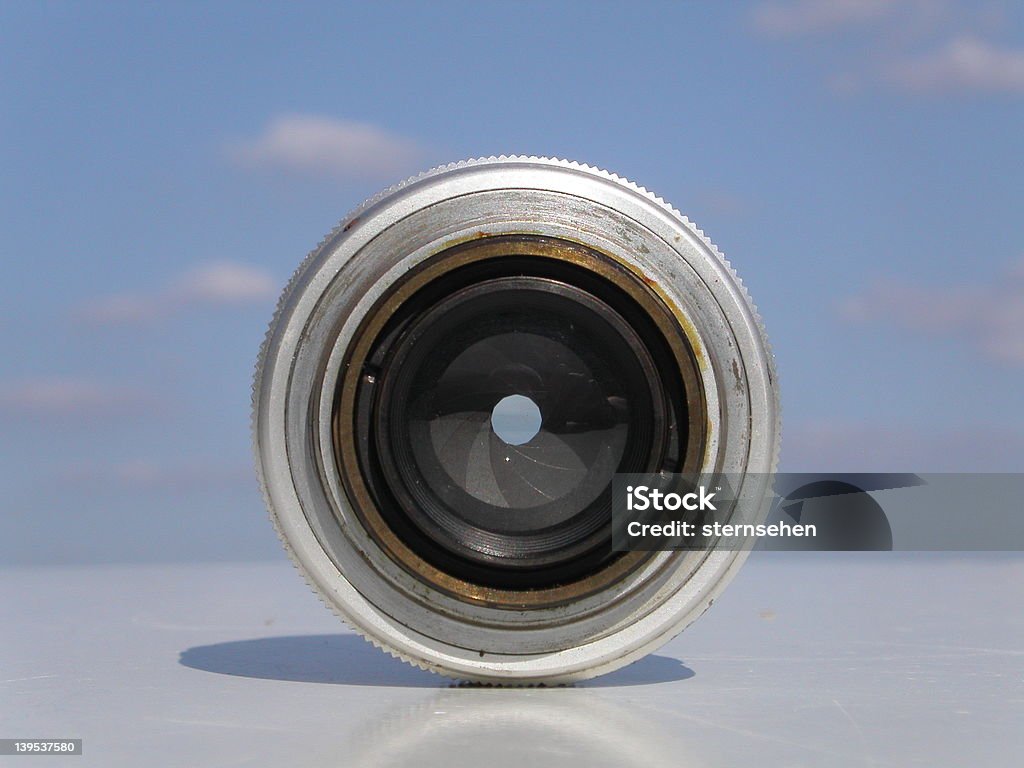 metaphysically objective straight close up of an old camera objective, lense, with vanishing horizon of the table and a light blue scattered sky in the background Accuracy Stock Photo