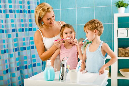 Mother showing their children proper way to brush teeth before going to sleep