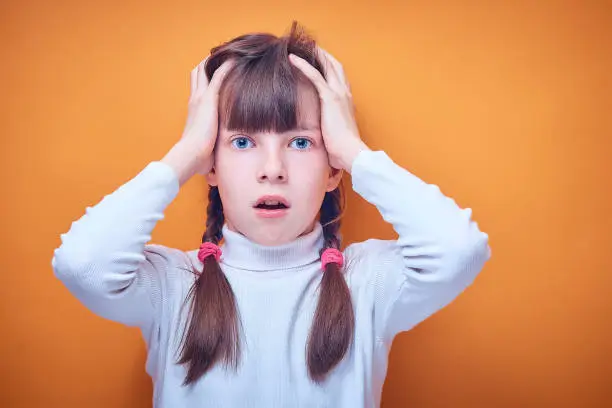 Photo of scared and surprised Caucasian teen girl on colored background, place for text