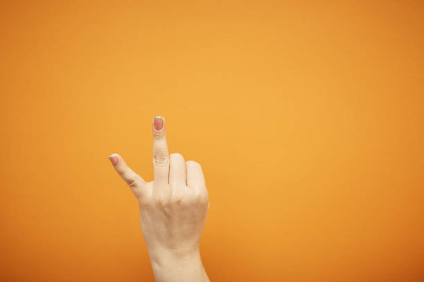 istock gesture, female hand shows two fingers isolated on orange background 1395380587