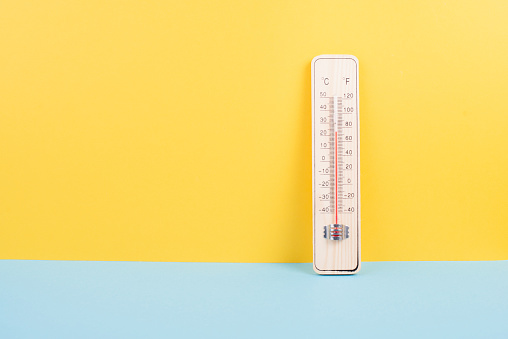Thermometer on a yellow and blue colored background, measure the temperature, weather forecast, global warming and environment discussion, summer season