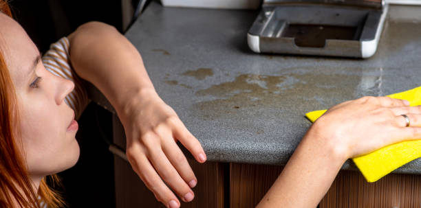 istock The coffee machine has broken down and needs to be repaired. The woman wipes the consequences with a rag. Leaked, spilling coffee on the kitchen table. 1395382574