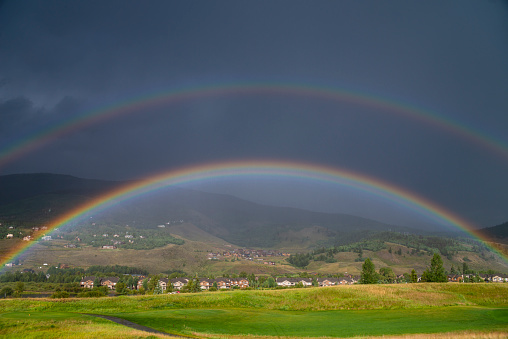 A double rainbow forms over a golf fairway during a rainstorme in the Rocky Mountains of Colorado.