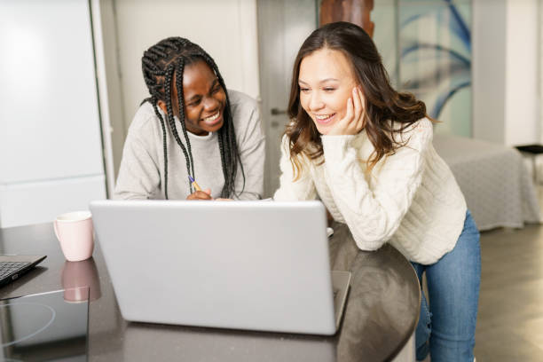 istock Two college girls studying together at home with laptops while drinking coffee 1395387509