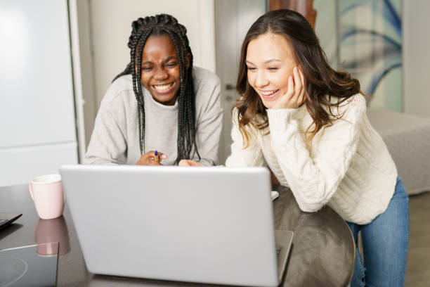 istock Two college girls studying together at home with laptops while drinking coffee 1395387511