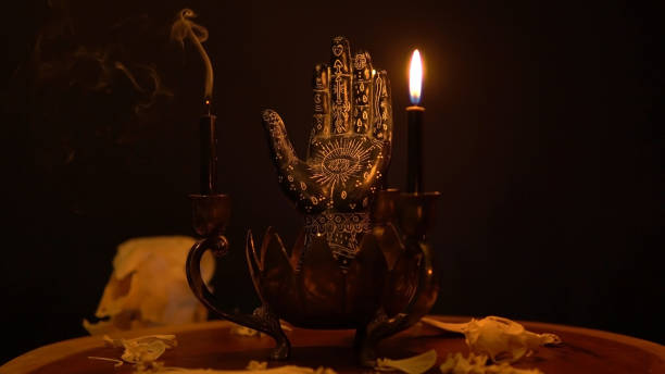 istock Fortune teller hand or palmistry on the witch table with animal bones. Palmistry with black palm and candles in the candelabra. Magic alchemy spirituality symbol. Palm reading in mystic, occult room. 1395391264