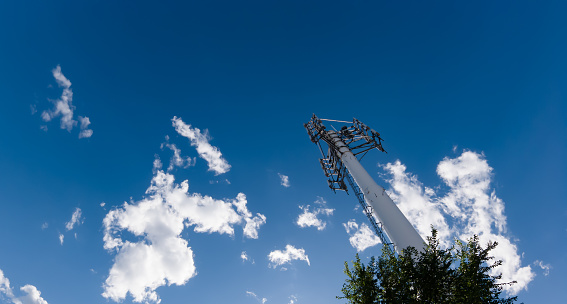 Mobile phone communication radio antenna, 3G, 4G, 5G, 6G. Antenna over cloudy blue sky at summer. Cellular GSM tower with transmitter. Telecommunication base station network.